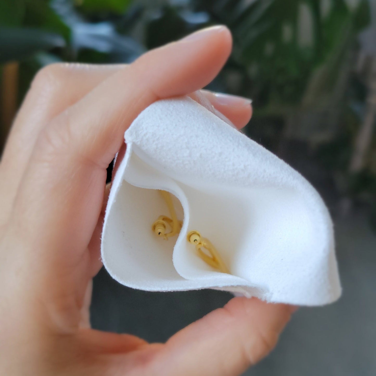 hand holding white velvet pouch, showing the to pockets inside to separate the earrings so they do not get scratched