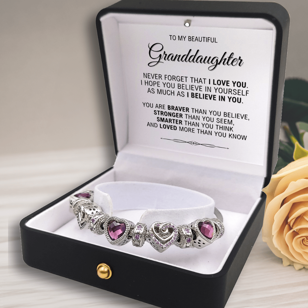 Silver bracelet with purple heart stones in a black box with a message for granddaughter, next to a yellow rose.