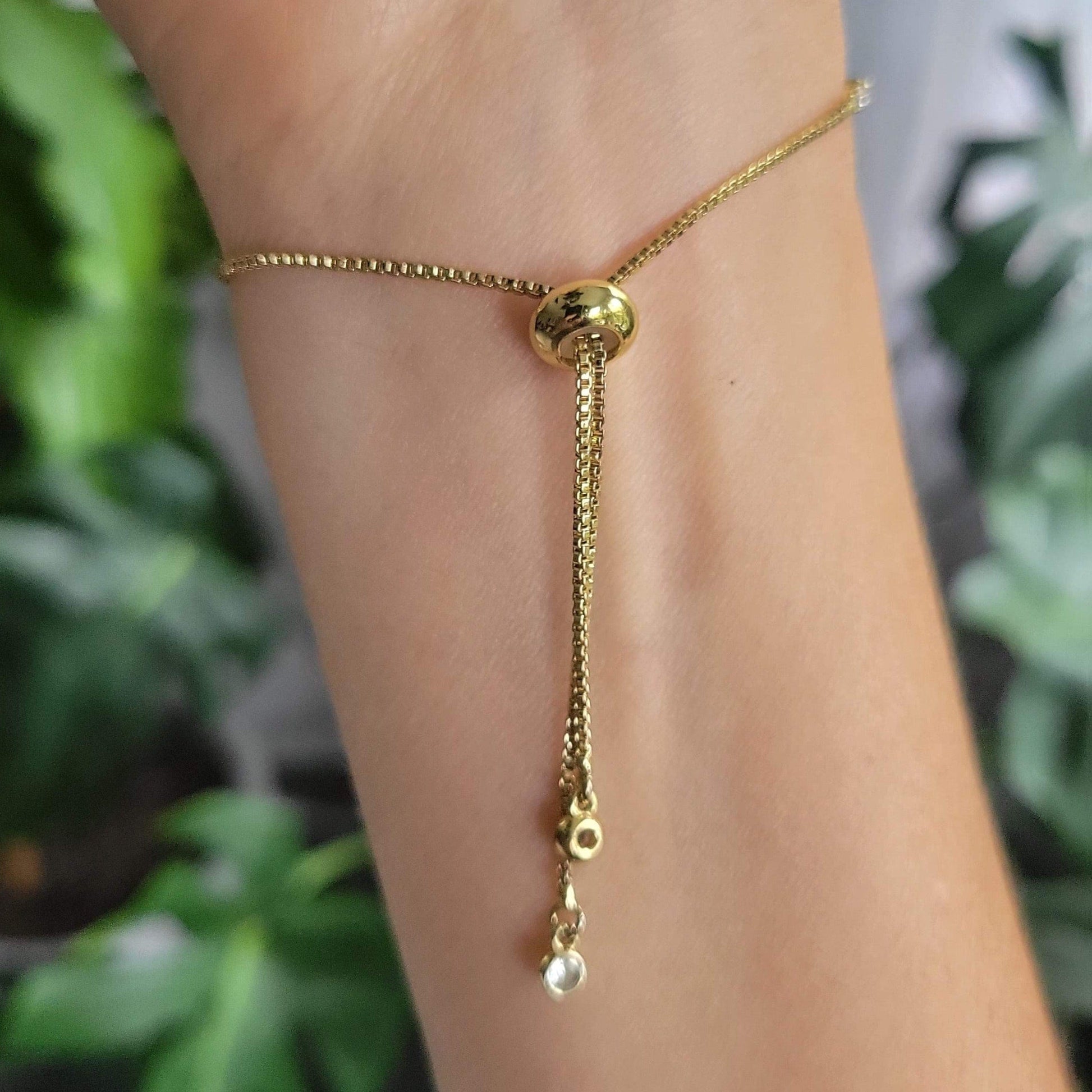 Gold bracelet on a person's wrist showing the adjustable bolo slide
