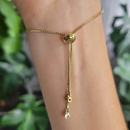 Gold bracelet on a person's wrist showing the adjustable bolo slide