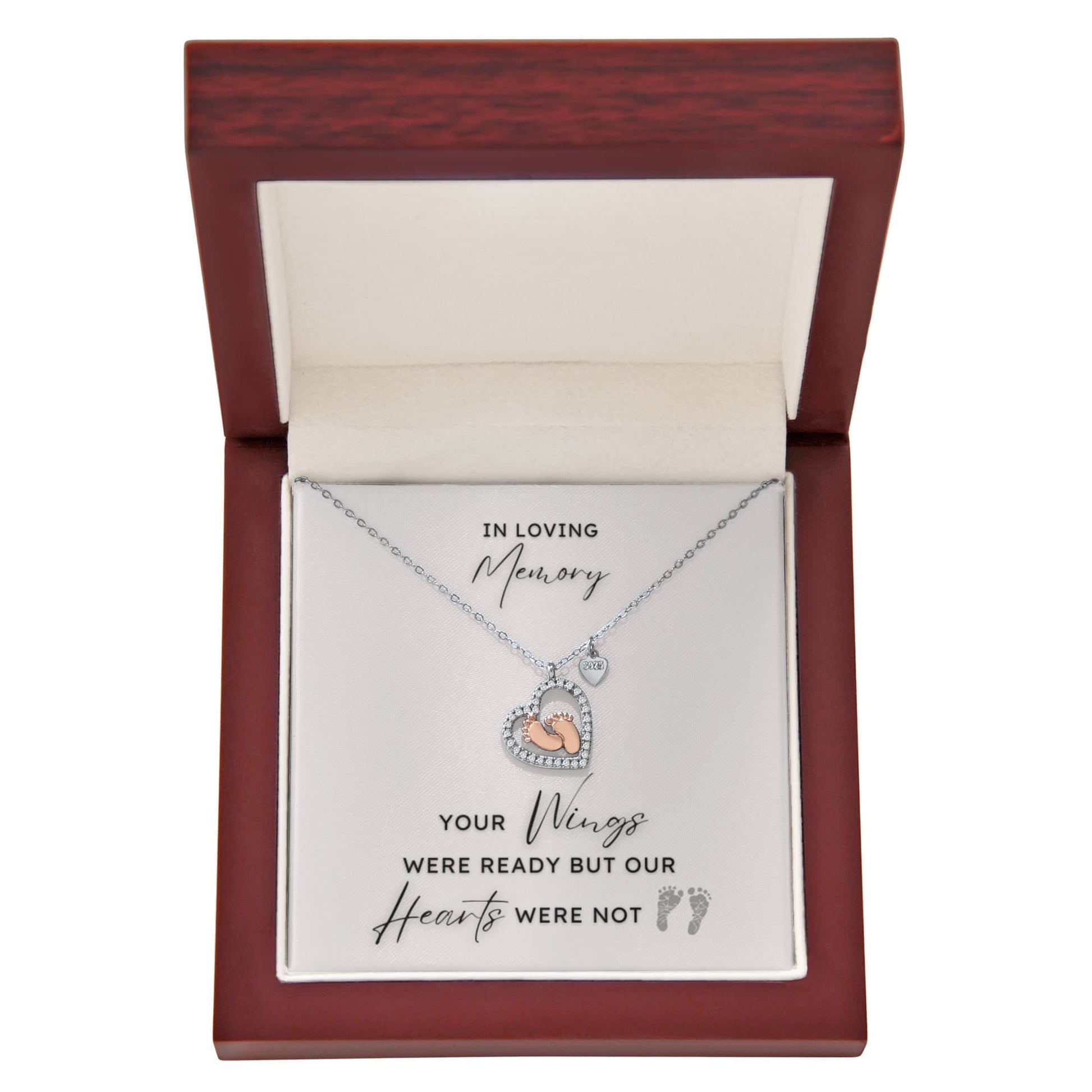 Necklace with a heart shape pendant with rose gold baby feet inside in a jewelry box with a message card.